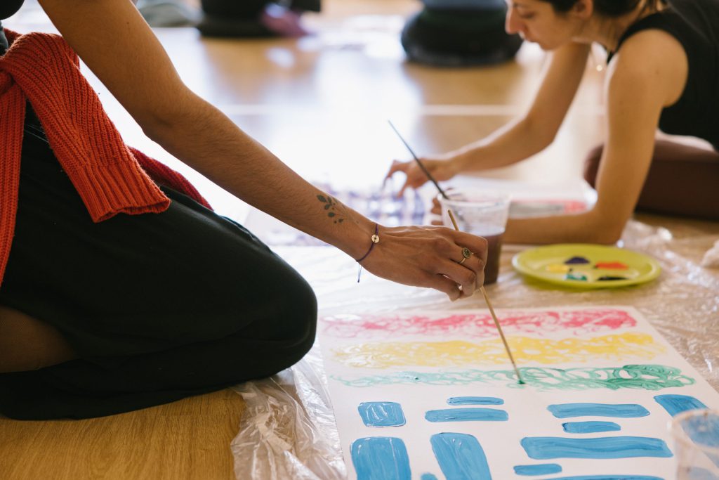 Manos de alumnas de la formación de máster en arteterapia gestalt, pintando sus polaridades.