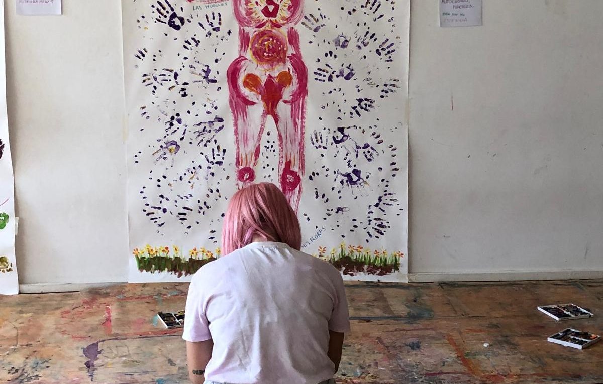 Sesiones abiertas y gratuitas de Arteterapia Gestalt 2 Cartografía corporal en pintura colgada de la pared con alumna de arteterapia tomando apuntes durante un Introductorio de Arteterapia Gestalt
